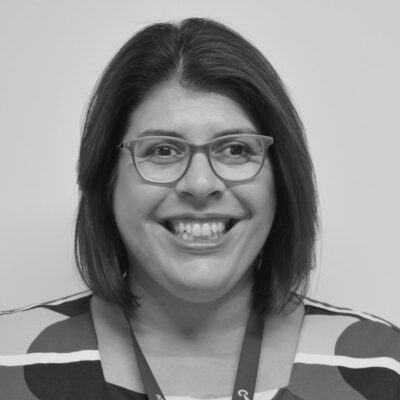 Image of a lady with a bob haircut, glasses, and big friendly smile.
