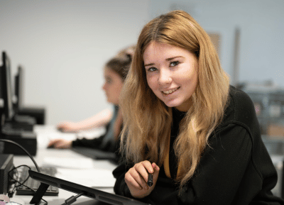 Student at her desk, looking to camera