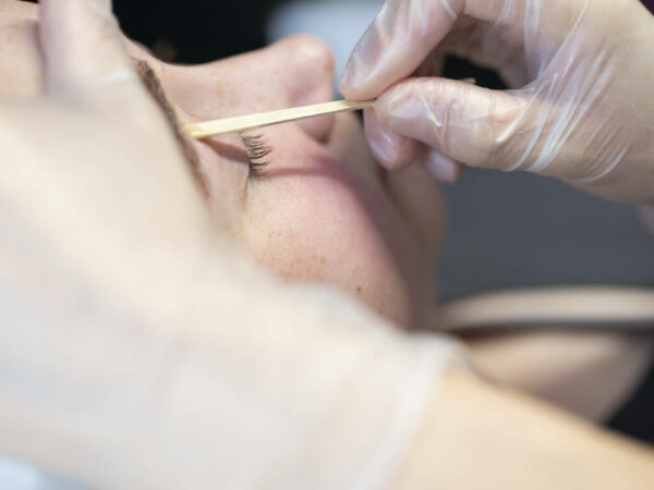 Beauty student waxing a clients eyebrow.