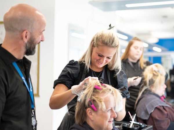 Hairdressing student and tutor working on a client