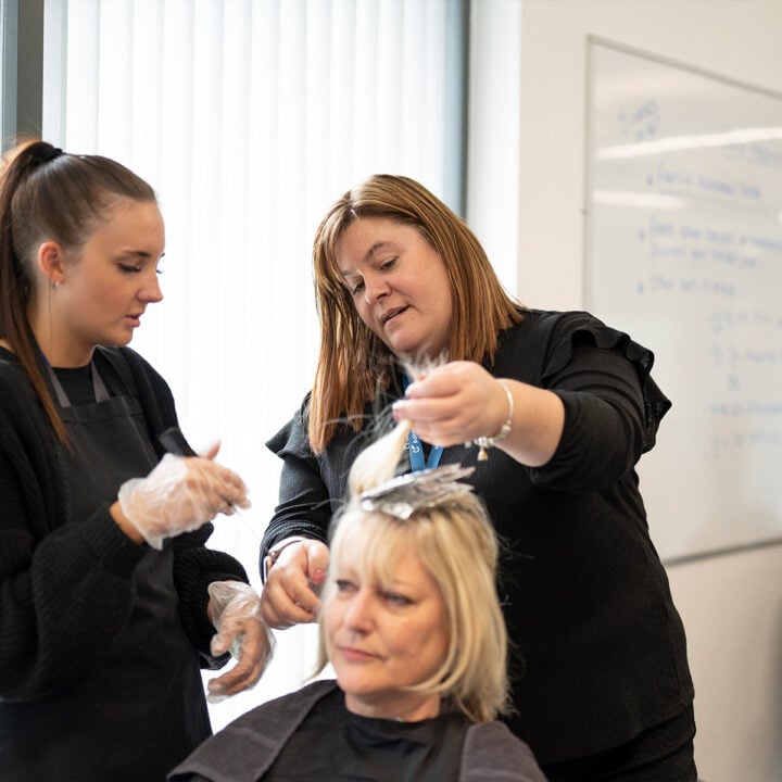 Hairdressing student and tutor working on a client