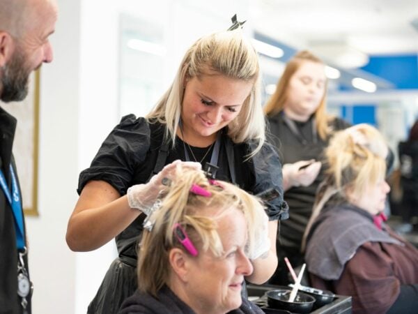 Hairdressing student and tutor working on a client