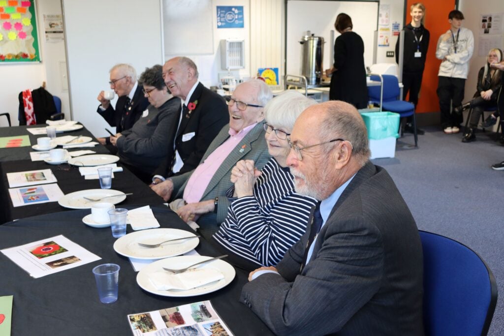 A group of people smiling sat at a long table