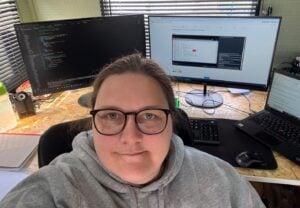 headshot of a woman in front of three computer screens