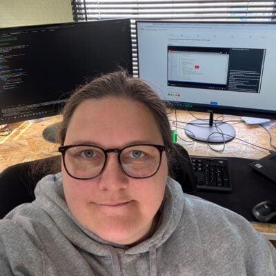 headshot of a woman in front of three computer screens