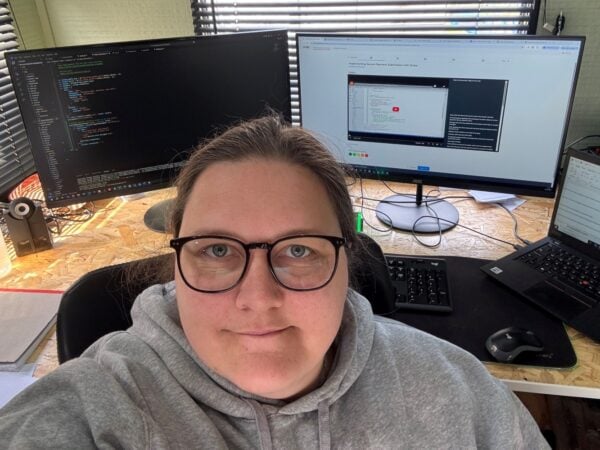 headshot of a woman in front of three computer screens