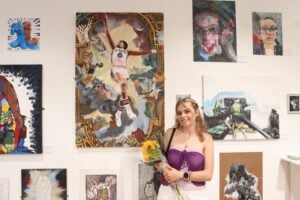 Young artist stood in front of art in gallery