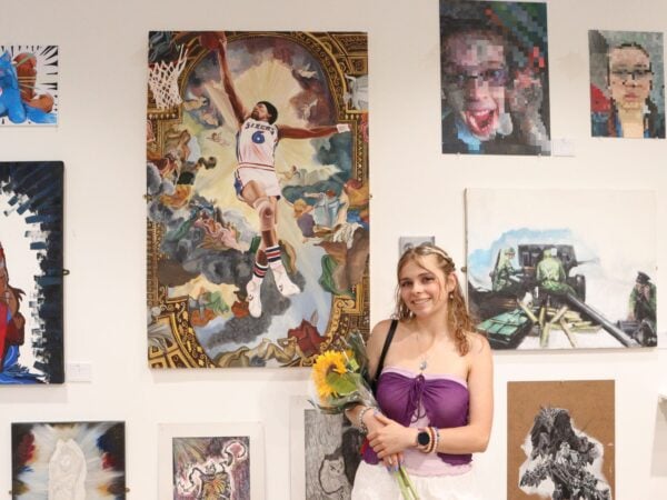 Young artist stood in front of art in gallery