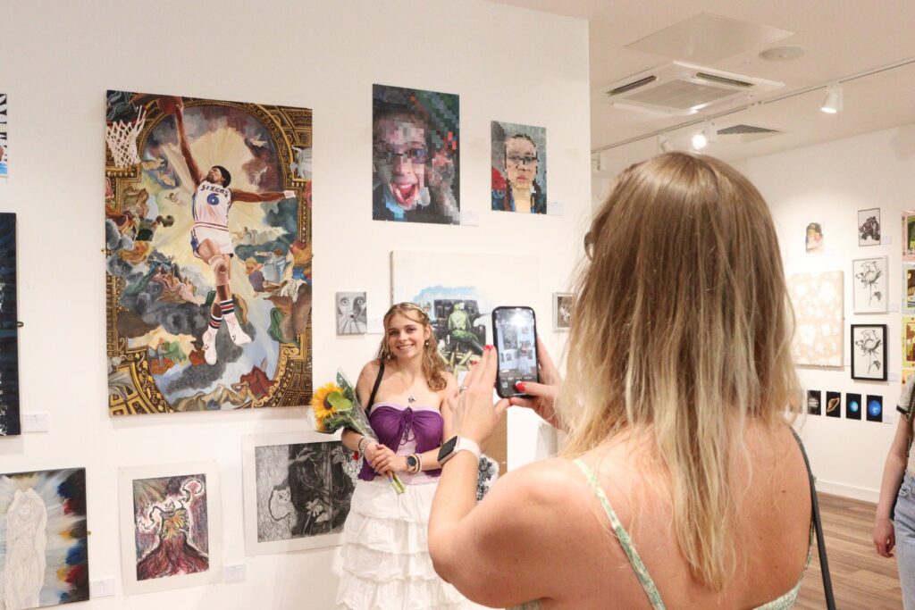 Young artist standing in front of painting posing for a photo