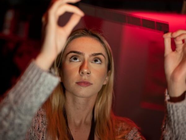 a student looking at a photo negative in a darkroom