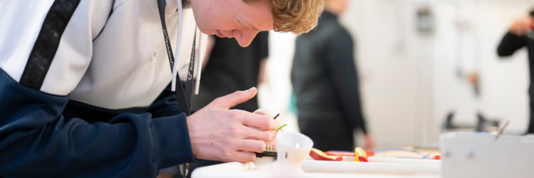 student at a workbench holding a screwdriver and working with a plug socket.