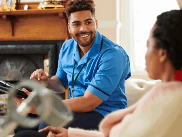 A care worker sat on a sofa with his client