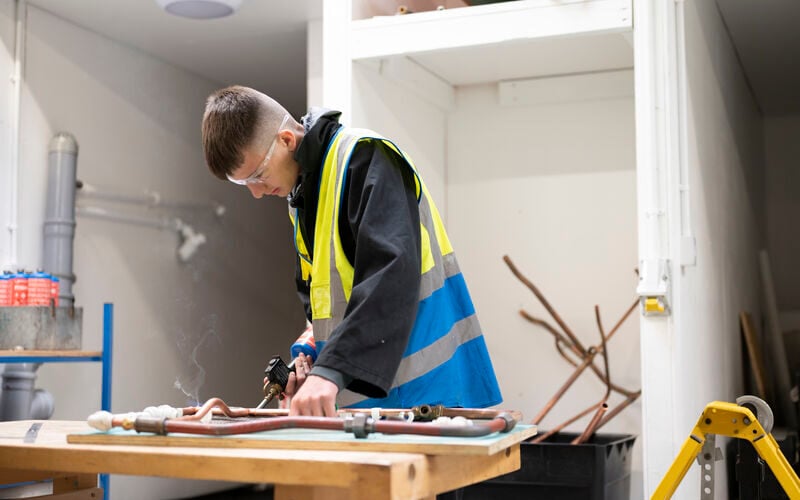 students soldering pipes on a workbench