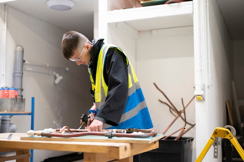 students soldering pipes on a workbench