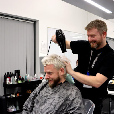 A man blow drying a customers hair