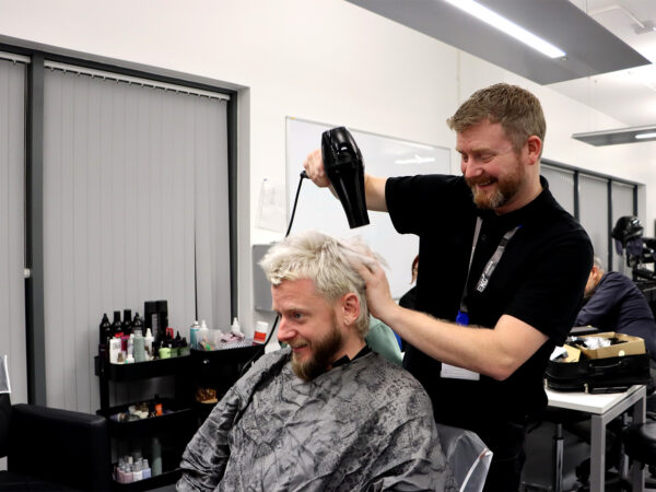 A man blow drying a customers hair
