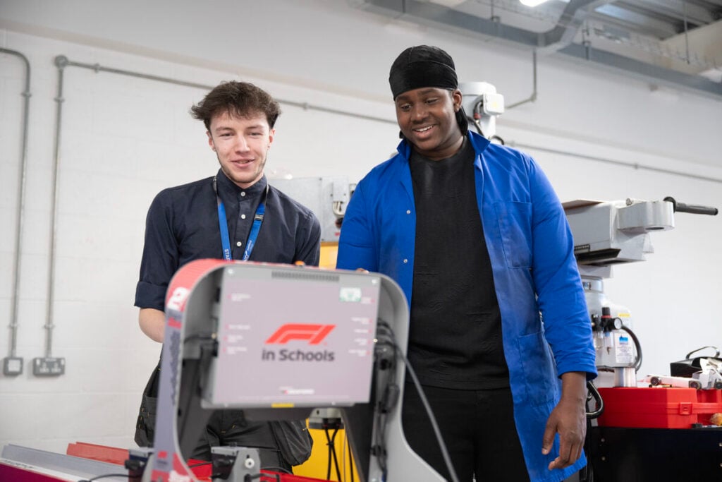 two students looking and smiling and engineering equipment