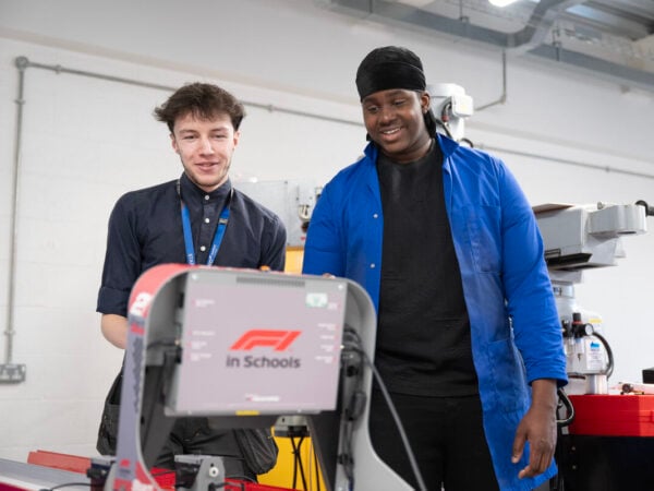 two students looking and smiling and engineering equipment
