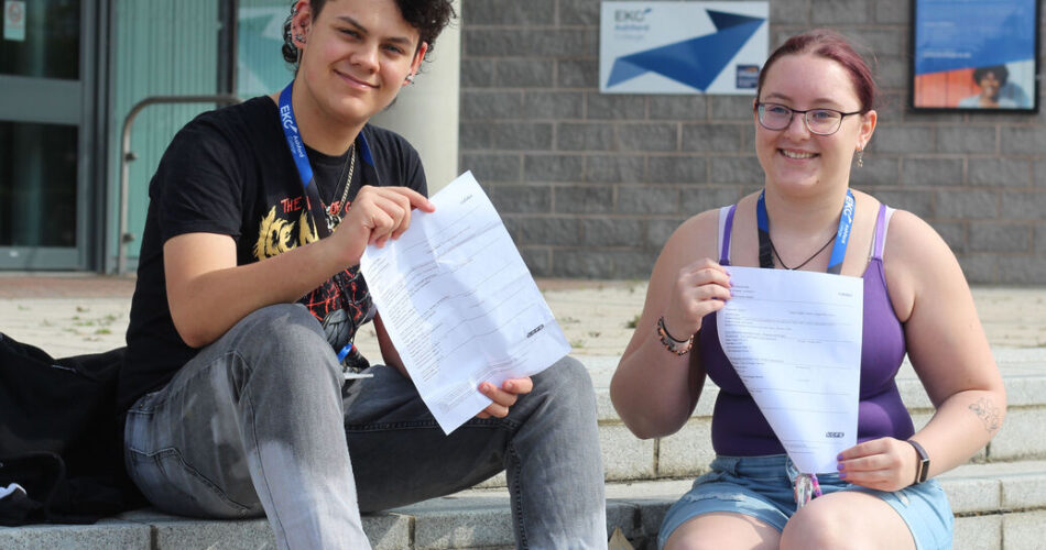 Two students sitting on the steps outside college smiling holding up their qualification papers.