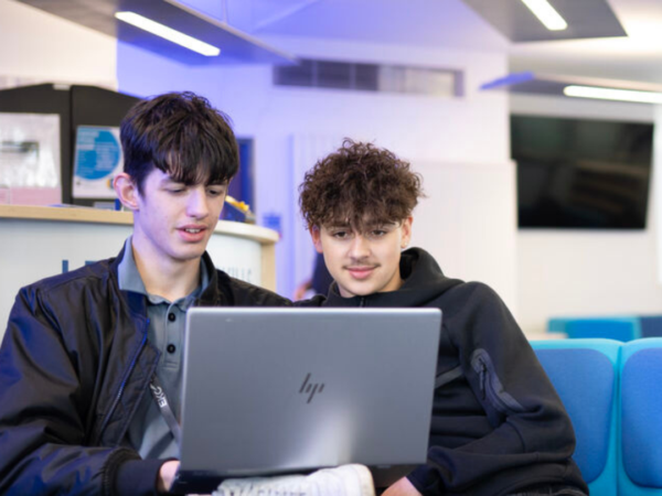 two students sitting on the comfy blue e-hub sofas looking at laptop