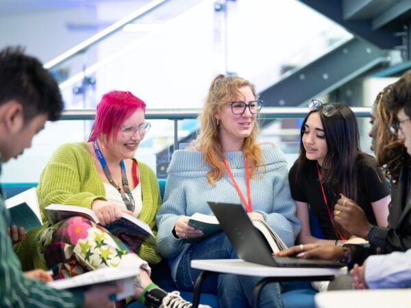 group of students sitting, talking and smiling to each other in the E-Hub