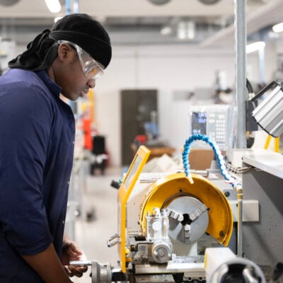 student using engineering equipment with goggles on
