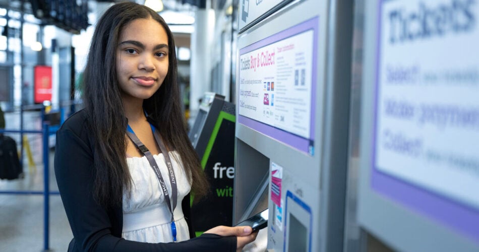 Student tapping her phone to pay for a train ticket at a machine.