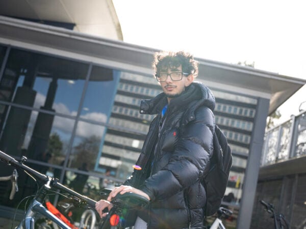Student outside the train station with a bicycle.
