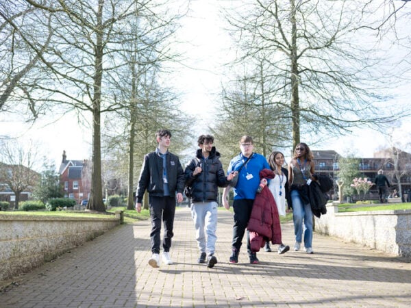 a group of students walking along a path, the sun is shing.