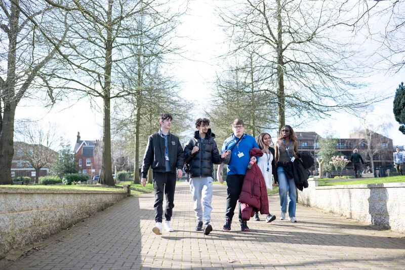 a group of students walking along a path, the sun is shing.