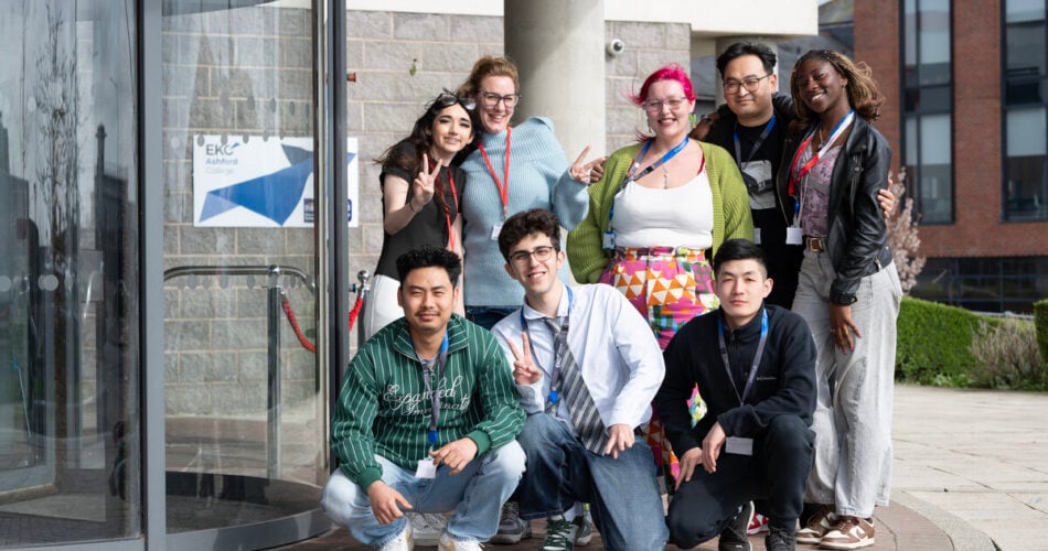 group of adult learners smiling at the camera outside the front of college