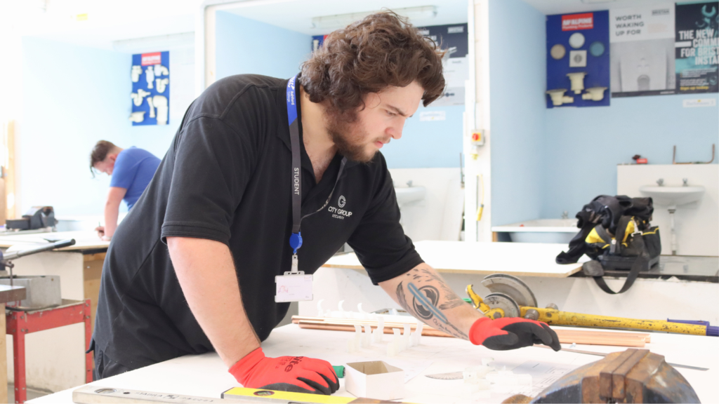 Student concentrating at competition paperwork on a workbench.