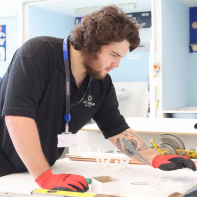 Student concentrating at competition paperwork on a workbench.