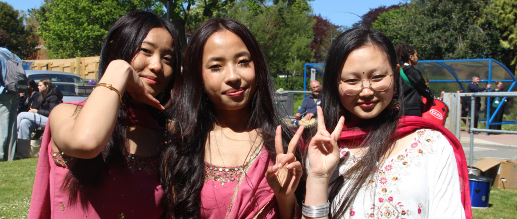 Three students smiling at camera, they all have black hair.