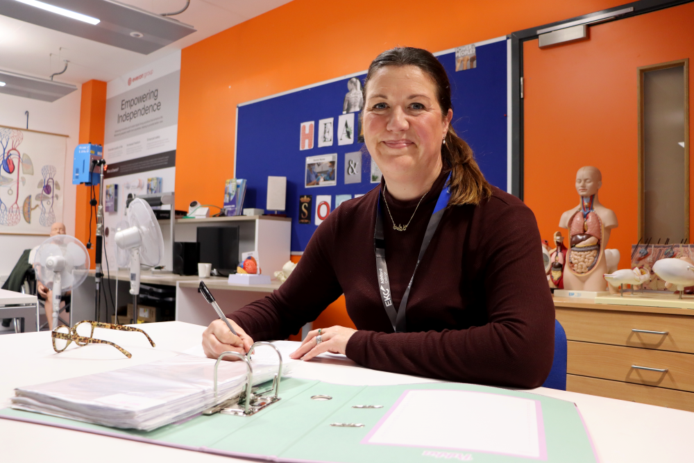 Lady in a classroom working using a folder