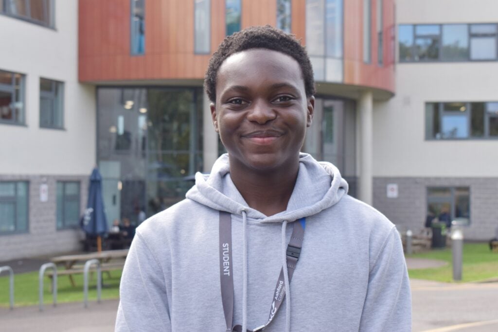 Student wearing a grey hoodie standing outside Ashford college smiling at the camera.