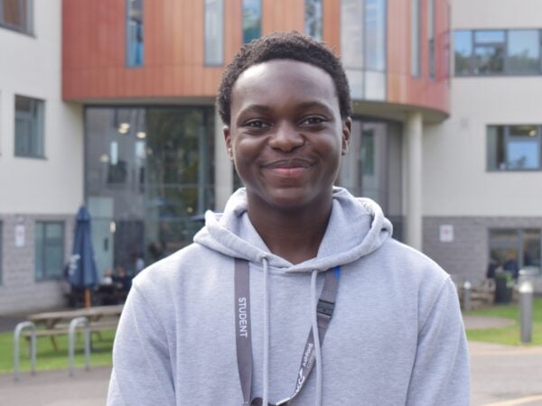 Student wearing a grey hoodie standing outside Ashford college smiling at the camera.