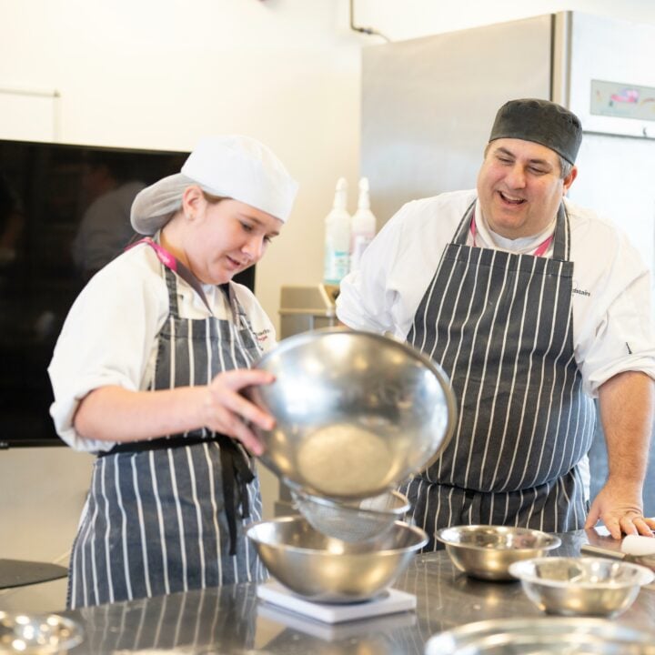 Catering student cooking with tutor