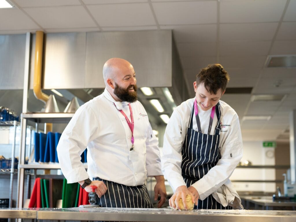 Catering student baking with tutor