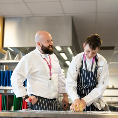 Catering student baking with tutor