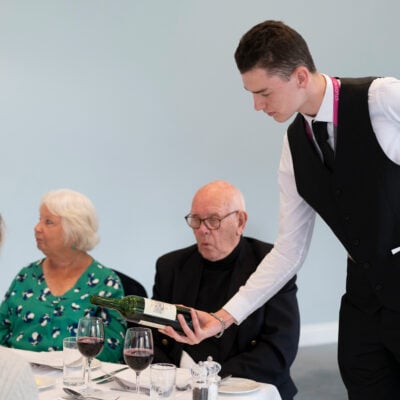 Hospitality student pouring wine for customers