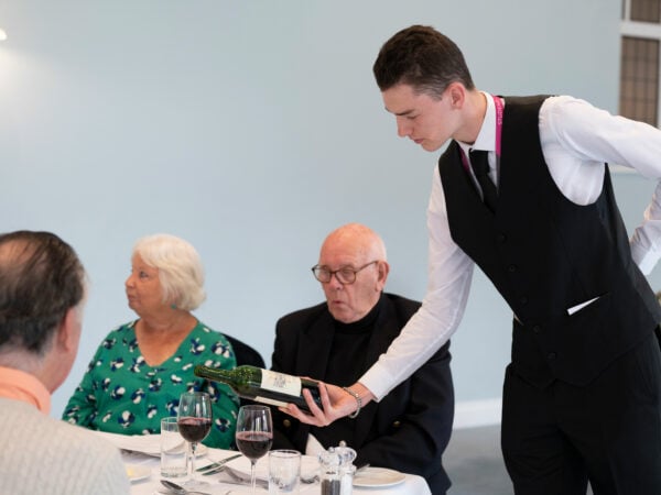 Hospitality student pouring wine for customers