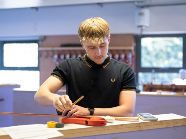 Student measuring and bending pipe work