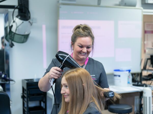 Adult student drying clients hair