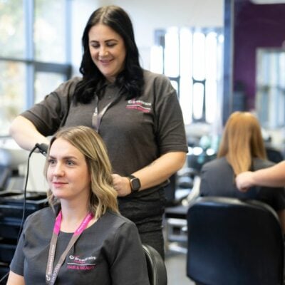 Hairdressing student styling client's hair in the salon