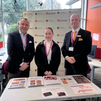 female student and two adult males working at a careers fair.