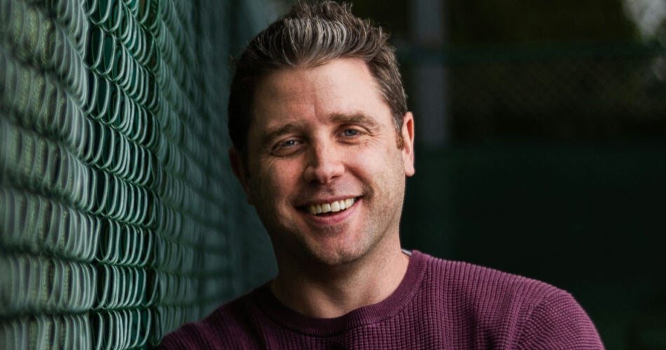 Adult leaning against a fence looking happy