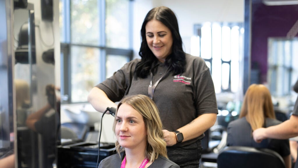 Hairdressing student styling client's hair in the salon