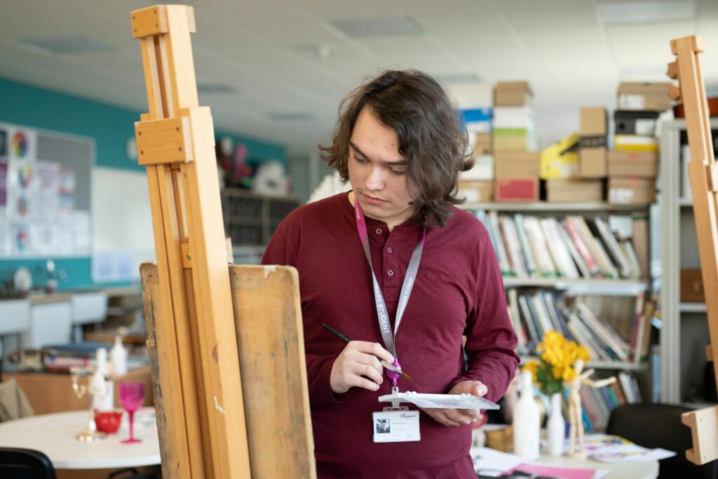 art and design student painting at an easel