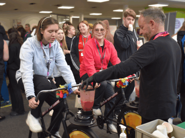 a female student rides an exercise bike to power a blender.
